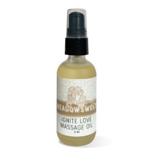 A frosted glass jar with a black pump that contains golden Ignite Love Massage Oil.
