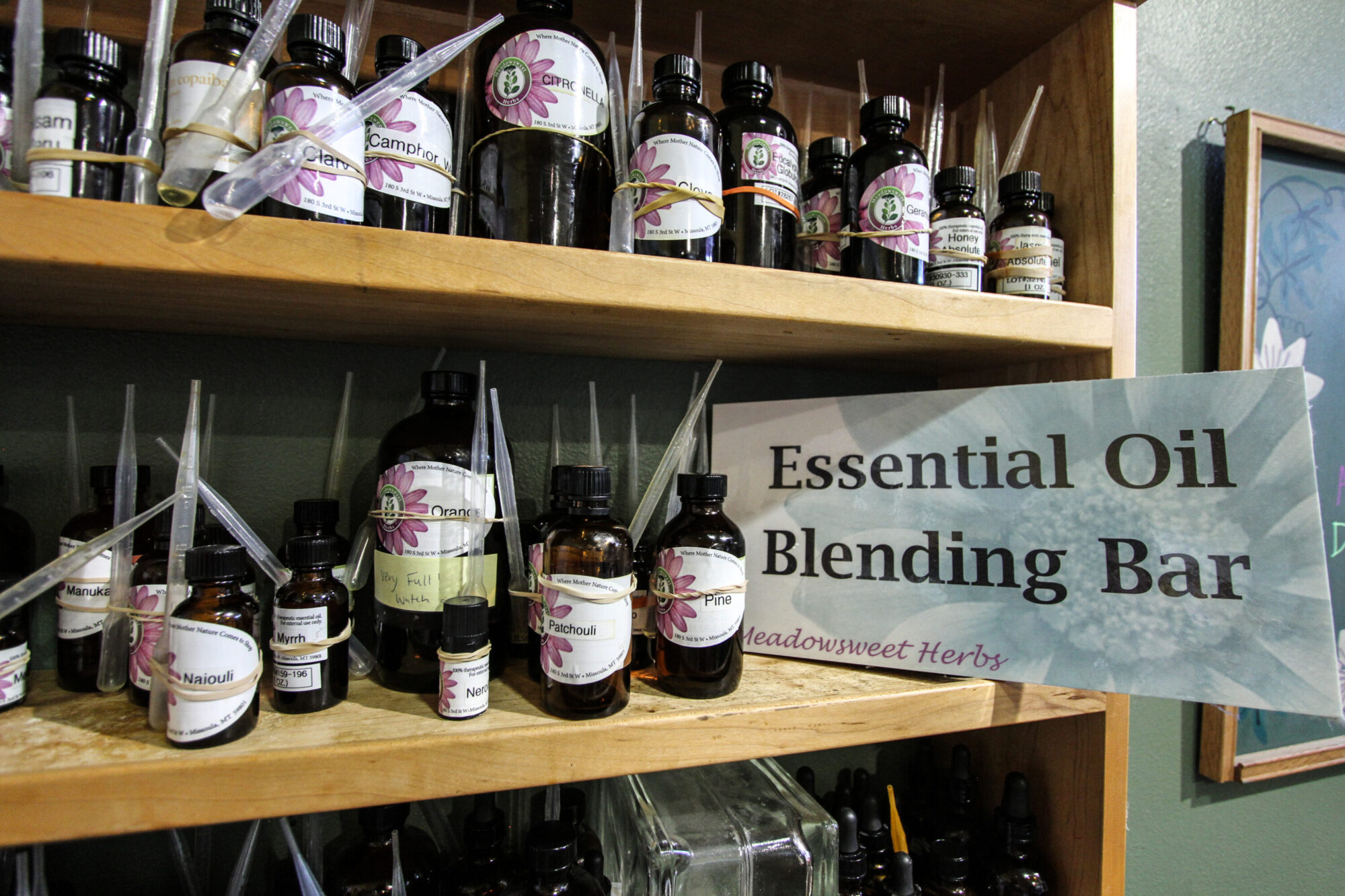 Essential oil bar #1 dozens of 1/2 ounce to 4 ounce brown bottles with plastic pipettes contain essential oils on a shelf